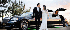 Newlyweds posing beside a white stretch limousine for wedding photography